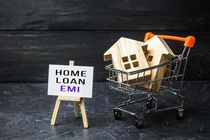 Houses in shopping cart and easel with home loan EMI. Equated Monthly Installment loan. Reducing debt with regular payments over loans period. Attractive interest rates, customized repayment options photo