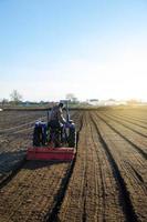 el tractor está cultivando la tierra en el campo agrícola. ablandamiento y mejora de las cualidades del suelo. preparándose para cortar filas para la próxima temporada de siembra en la primavera. agricultura. foto