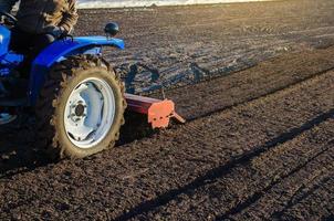 A farmer on a tractor cultivates a farm field. Softening the soil and preparing for cutting rows for the next sowing season in the spring. Land cultivation. Small farms. Work in agricultural industry photo