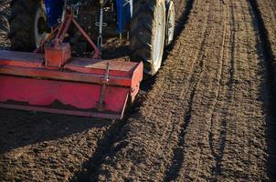 el tractor cultivador rompe y mezcla el suelo, dándole suavidad y humedad para seguir cortando en hileras. pequeñas granjas. trabajo en la industria agrícola. maquinaria de agricultura foto