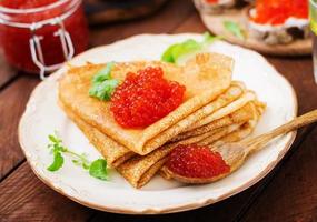 Pancakes with red caviar on plate. Russian cuisine. Maslenitsa photo