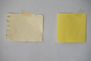 blank sticky note paper for mockup. cream memo glued with tape on the wall photo