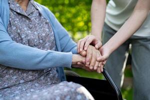 Caregiver holding hands Asian elderly woman patient, help and car in hospital. photo