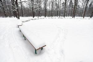 snow covered public area with benches in city park photo