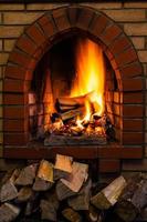 wood stack and logs burning in brick fireplace photo