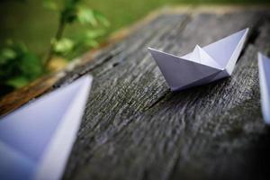 origami, barco de papel blanco aislado en un piso de madera. Los barcos de papel significan caminar. sentimiento de libertad liderazgo foto
