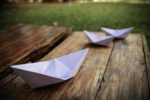 Origami, white paper boat isolated on a wooden floor. Paper boats mean walking. feeling of freedom leadership photo