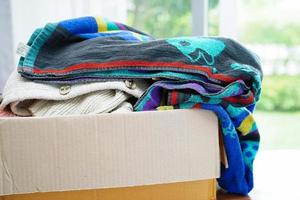 Clothes donations in cardboard box for volunteer. photo