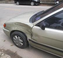 Gold color car's dent beside left wheel from an accident. photo
