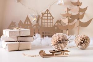 decoración casera navideña de bricolaje: bola de papel en trineo, regalos de papel artesanal, árbol de cartón y casa. foto