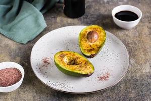 Avocado halves with black himalayan salt on a plate on the table photo