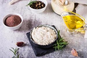 Sesame tahini with black salt in a bowl and cooking ingredients on the table photo