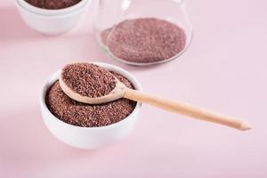 Black Himalayan kala namak salt in bowl with wooden spoon on pink background photo