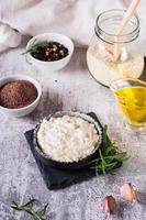 Sesame tahini with black salt in a bowl and cooking ingredients on the table. Vertical view photo