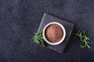 Black Himalayan kala namak salt in a bowl and rosemary on a black background. Top view. photo