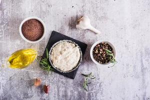 salsa tahini de semillas de sésamo en un bol e ingredientes para cocinar sobre la mesa. vista superior foto