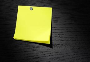 papel de nota amarillo sobre fondo de madera oscura foto