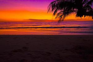 Silhouette of beautiful sunset on the sea beach with palm tree, sky on twilight time and reflection on the sea.for travel in holiday relax time, photo