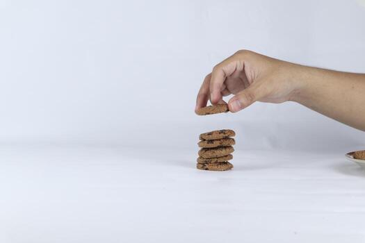 hands stacking cookies on a white background. Human hand taking oat cookie from a stack photo