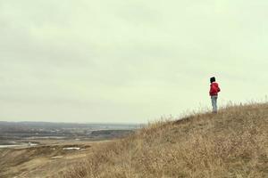 A man is standing on a hill. A time of calm and tranquility. Nice view from the hills to the fields photo