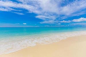 Closeup sea sand on beach and blue summer sky. Panoramic beach landscape. Empty tropical beach and seascape. Relax pristine water reflection, surface, horizon. Tranquil amazing ocean view. Seascape photo