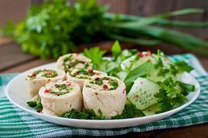 Steamed chicken rolls with greens and fresh vegetable salad on a brown plate photo