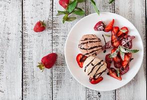Ice cream with strawberries and chocolate on a white plate photo