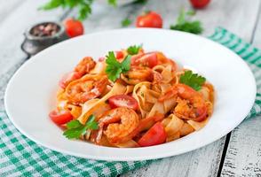 Fettuccine pasta with shrimp, tomatoes and herbs photo