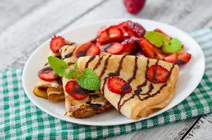 Pancakes with strawberries and chocolate decorated with mint leaf photo