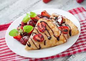 Pancakes with strawberries and chocolate decorated with mint leaf photo