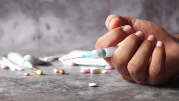 Hand with syringe, a lot of pills spread out video