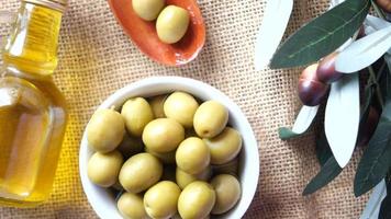 Small potatoes in a bowl, olive oil, olive branches, top view video