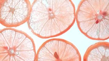 Juicy lemon slices with bubbles under water isolated on white background. Orange lime slices pattern textured background. video