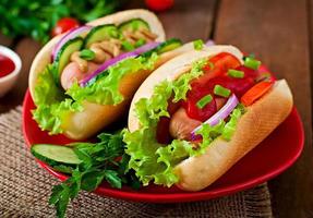 Hotdog with ketchup, mustard, lettuce and vegetables on wooden table photo