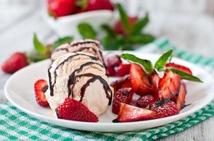 Ice cream with strawberries and chocolate on a white plate photo
