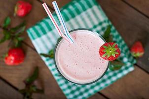 Strawberry milkshake smoothie with fresh strawberry on a wooden background photo