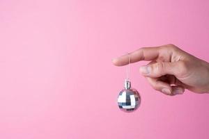 shiny christmas ball hanging on woman finger, christmas decorations photo