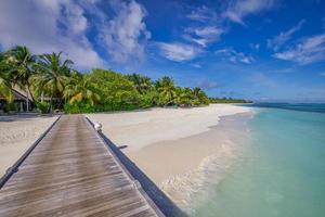 Beautiful tropical Maldives island relaxing scene blue sea, blue sky holiday vacation background. Wooden pathway, pier. Amazing summer travel concept. Ocean bay palm trees sandy beach. Exotic nature photo