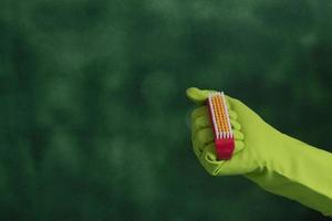 hand with protective glove holding packaging of cleaning products used for home hygiene photo