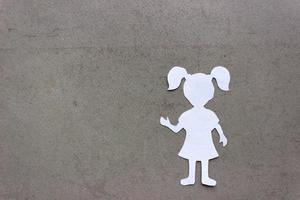 Silhouette of a girl in a dress and with ponytails made of white paper, cut by hand. In the right side of the photo. On beige background with copy space photo