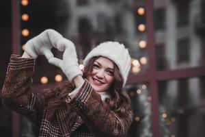 mujer feliz en mitones muestra forma de corazón foto