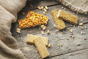 Mix of Gozinaki bar of seeds on a vintage background with burlap. Delicious oriental sweets from the seeds of sunflower, sesame and peanuts, covered with honey with shiny glaze. Macro Country Style photo