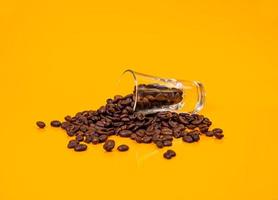 Dropped Many roasted coffee beans in a glass, in bucket jar. self-tapping screw for metal, for iron, chrome-plated self-tapping screw, orange yellow background photo