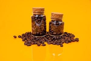 Dropped Many roasted coffee beans in a glass, in bucket jar. self-tapping screw for metal, for iron, chrome-plated self-tapping screw, orange yellow background photo