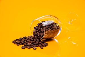 Dropped Many roasted coffee beans in a glass, in bucket jar. self-tapping screw for metal, for iron, chrome-plated self-tapping screw, orange yellow background photo