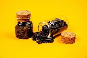 semillas de girasol negras en copa de vino de tarro de cristal. en cubo de semillas de girasol sobre fondo amarillo anaranjado. semillas de girasol de vista frontal, foto