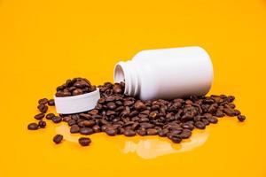 Dropped Many roasted coffee beans in a glass, in bucket jar. self-tapping screw for metal, for iron, chrome-plated self-tapping screw, orange yellow background photo