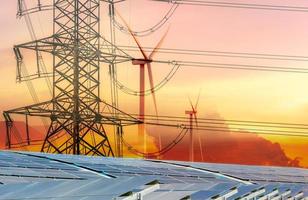 Sustainable energy. Solar farm, wind turbine, and electric pylon with sunset sky. Sustainable resources. Solar, wind power. Renewable energy. Green energy. Carbon neutrality and net zero emissions. photo