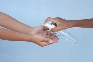 The older brother holds a bottle of alcohol spray, Sprayed into the sister's hand. To kill the Novel Coronavirus disease or Covid-19 photo