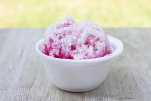 hielo raspado en una taza de espuma blanca sobre una mesa de madera, dulces adecuados para el verano. foto